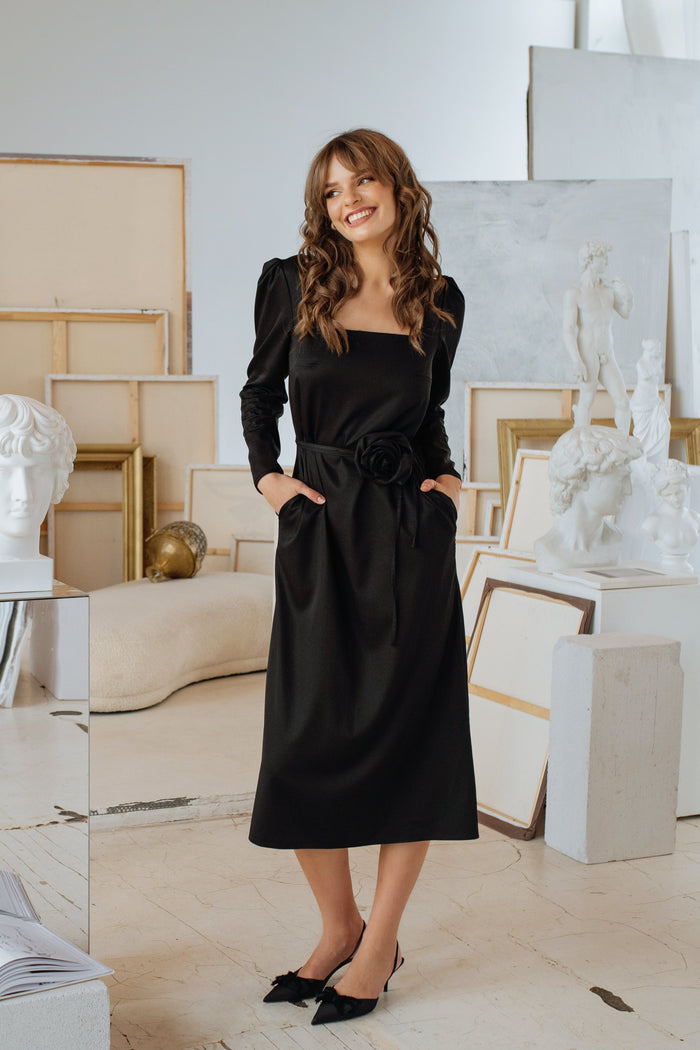 Model wearing the elegant dress with the rose belt tied at the waist, showcasing a structured silhouette and gathered shoulders.