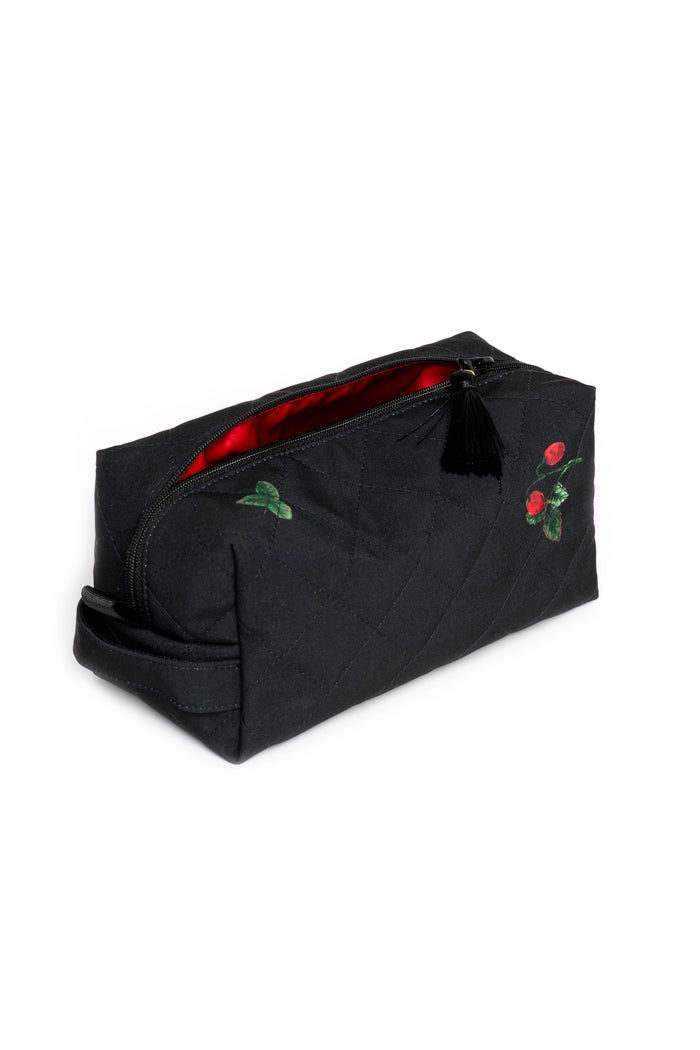 Small black makeup pouch with strawberry print opened to reveal red lining and compact storage for beauty essentials