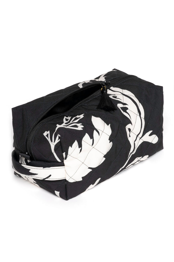 Large black travel makeup bag with white floral print opened to show black lining and spacious cosmetic storage compartment