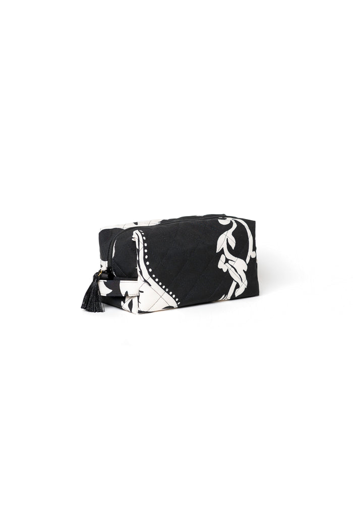 Small black cosmetic bag with white floral print, black zipper, and tassel detail for makeup, skincare, and travel accessories