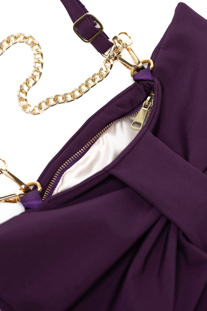 Close-up of a purple clutch bag with gold chain detail