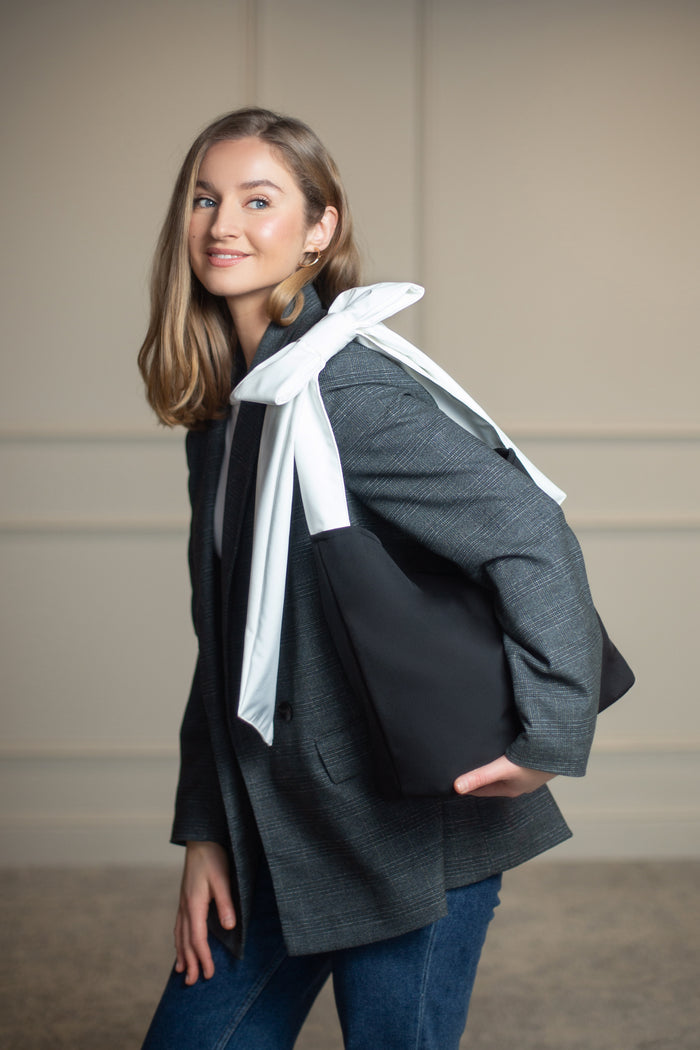 Spacious black tote bag with sturdy base, stainless steel feet, and nice interior; perfect for work, errands, or everyday wear.