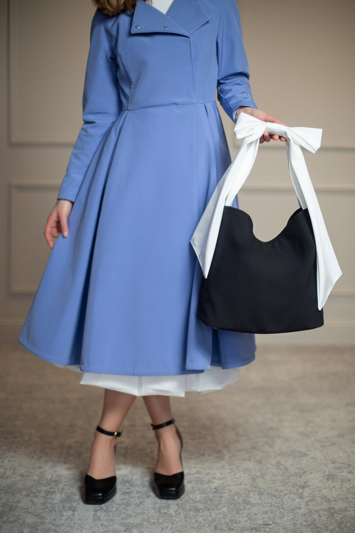 Water-resistant black tote with firm interior lining, stainless steel feet, and delicate bow accent—where functionality meets timeless style.