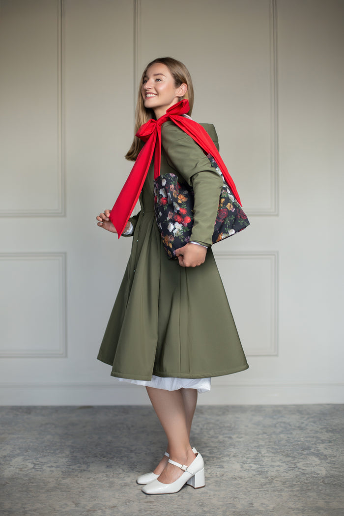 Darling Rose front view image, displaying vivid floral artwork and a prominent red bow handle styled tigether with RainSisters Moss Green coat.