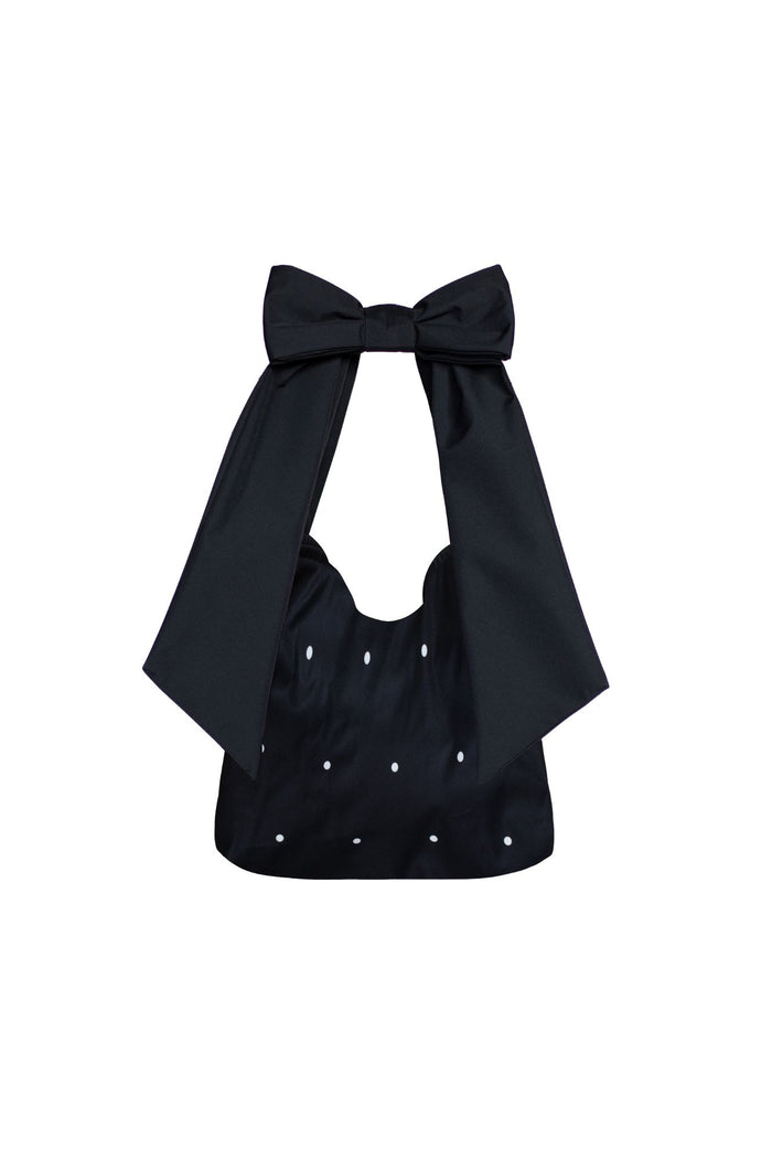 Black tote bag with bow detail and white polka dot print on a white background