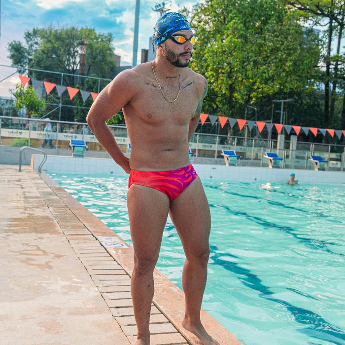 Male swimmer in a red Cherry Bomb swim brief made from recycled ocean plastic during pool practice.