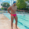 Male swimmer in a red Cherry Bomb swim brief made from recycled ocean plastic during pool practice.
