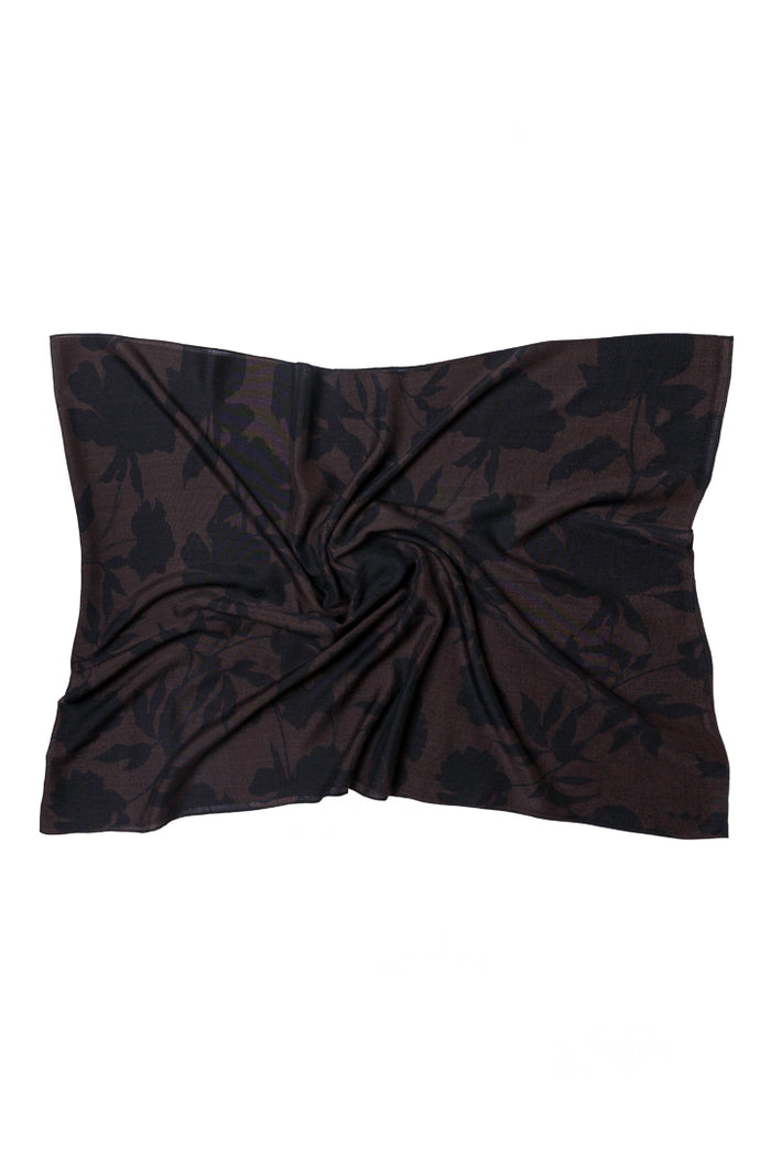 A brown scarf of wool and silk fabric with a subtle tonal floral pattern, styled with a central twist on a plain white background.