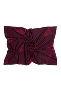 A dark plum purple scarf with a subtle tonal floral pattern, styled in a central twist on a plain white background.