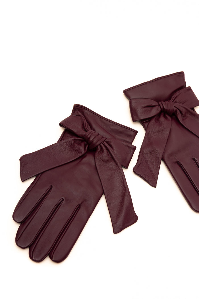 A pair of dark burgundy leather gloves with wide wrist bows, displayed on a clean white background.