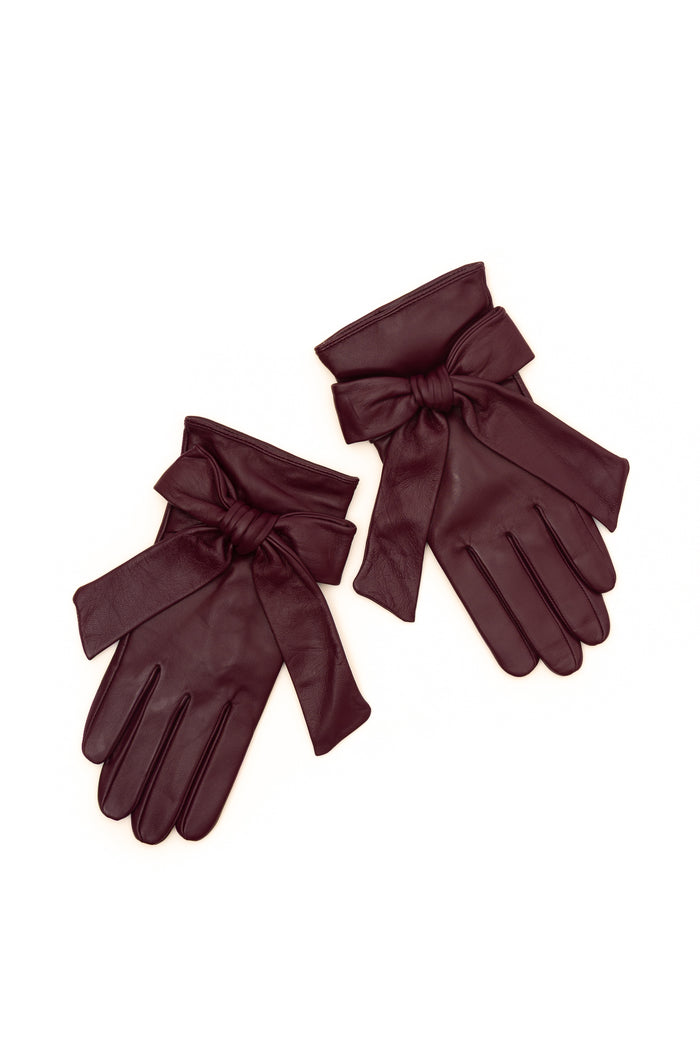 A pair of dark burgundy leather gloves with wide wristbands and large bow details, displayed on a clean white background.