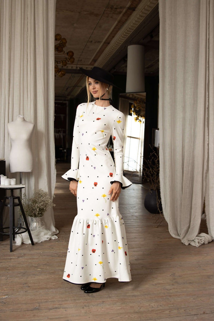 White viscose maxi dress with colorful floral accents and tiny black polka dots, ruffled hemline, and feminine flowing design.