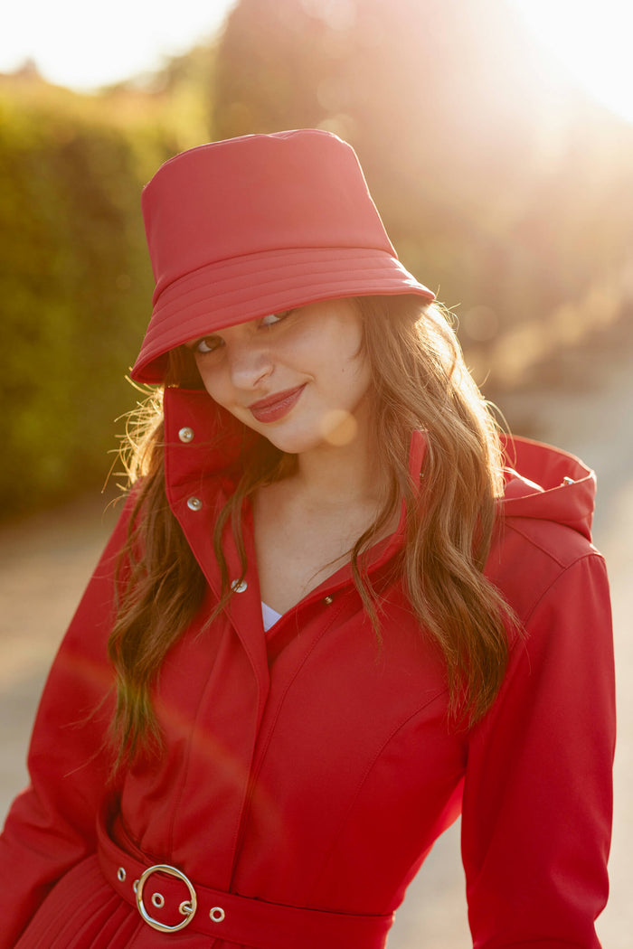 Woman wearing a red coat and a red hat with a natural background.