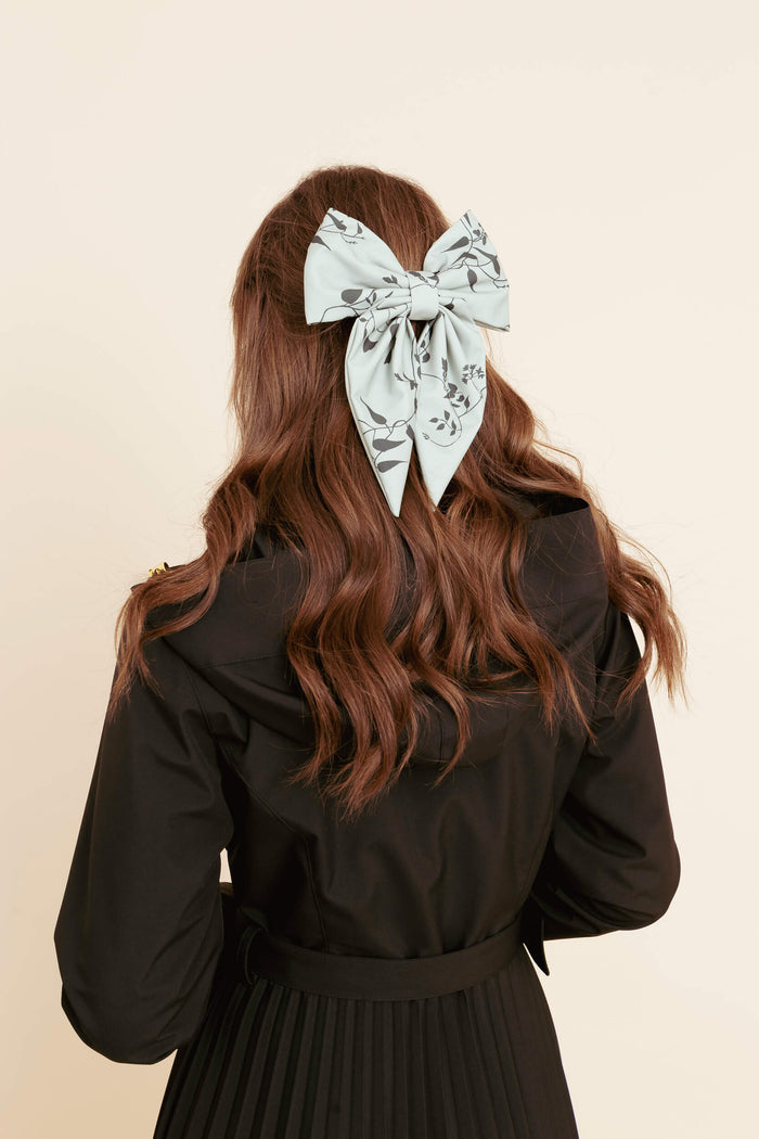 Model wearing a large accessory hair bow on a plain background