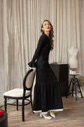 Elegant long sleeve black maxi dress with flared hem and feminine off-white ruffles, perfect for special occasions.