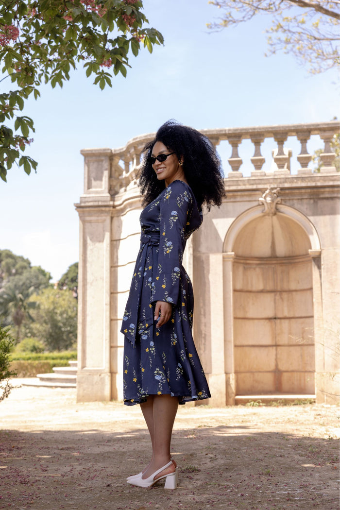 Woman wearing the Meadow Dream midi dress with soft flowing skirt, open shoulder detail, and long sleeves