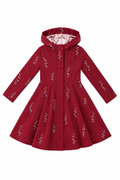 A red hooded raincoat with long sleeves and a flared skirt, decorated with small lily of the valley white floral patterns, shown against a plain white background.